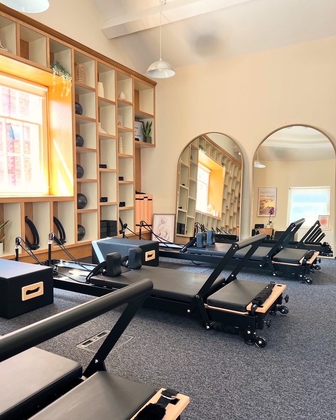 The Reformer studio at Casa Pilates, with oak shelving, arched mirrors and warm pendant lights