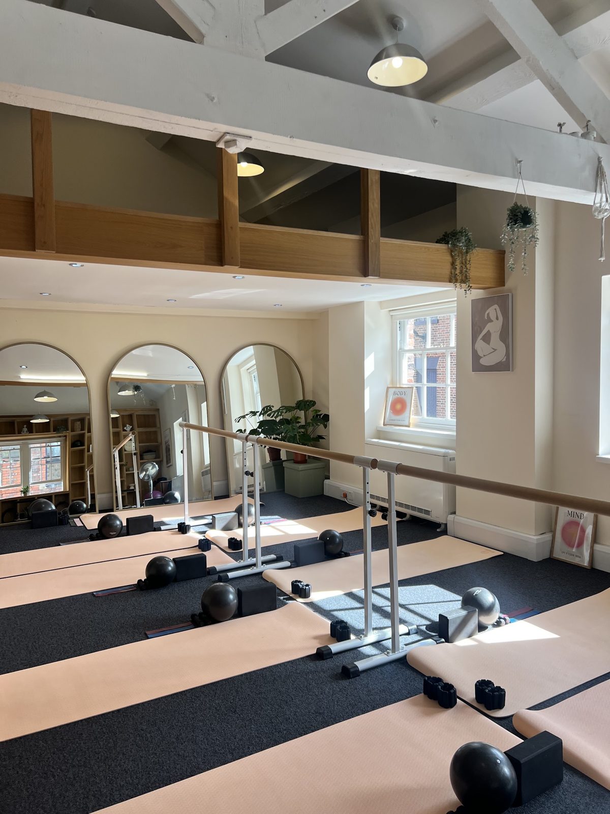 The mat and barre room at Casa Pilates: pink mats laid out in front of three arched mirrors