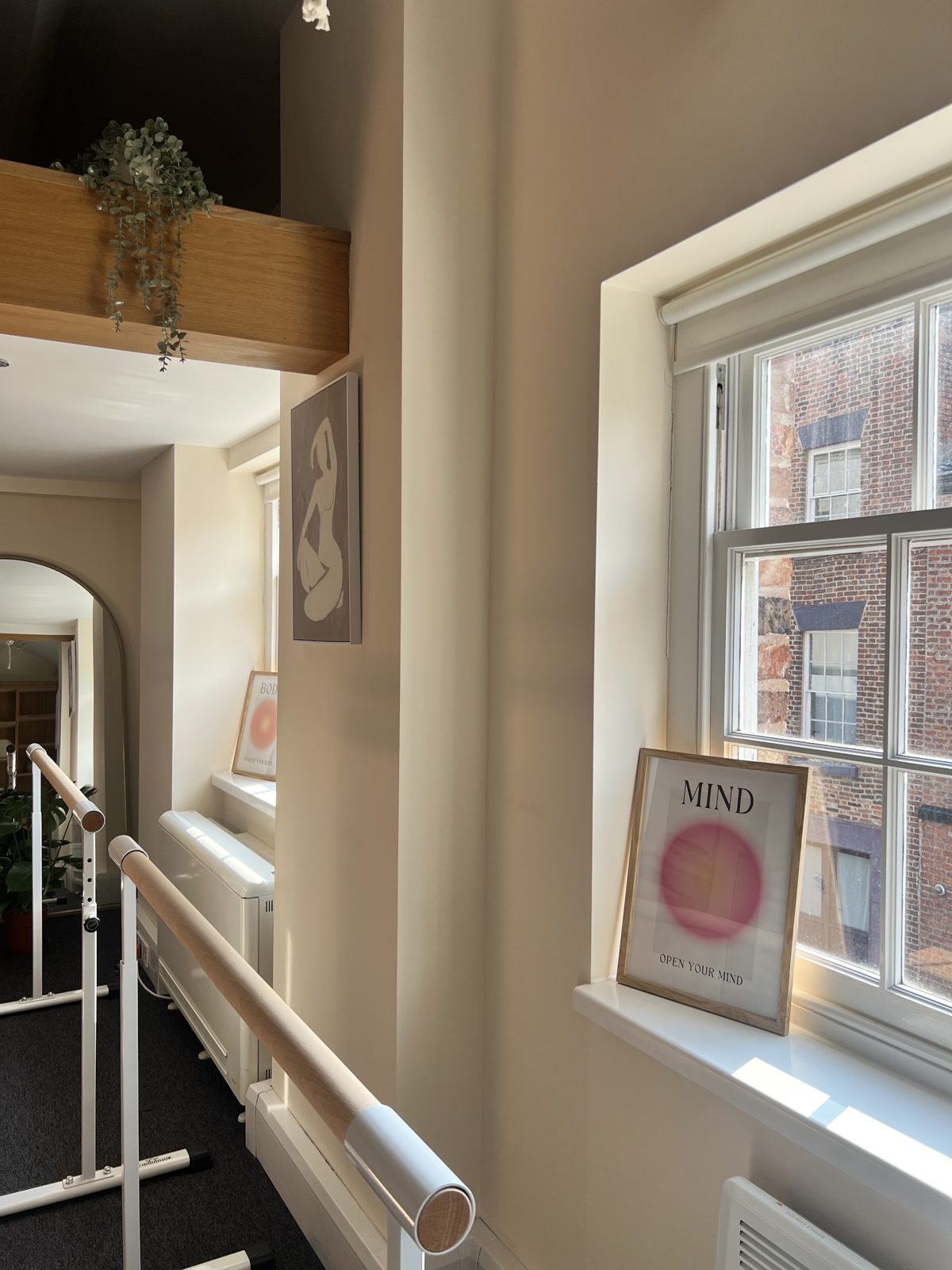 The ballet barre by the sash window in the studio, with a framed print on the sill
