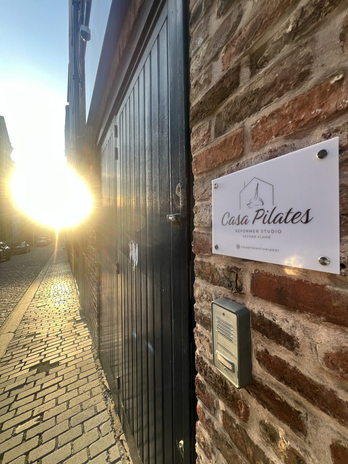 The Casa Pilates plaque and door buzzer on a brick wall beside a black door on Henry Street