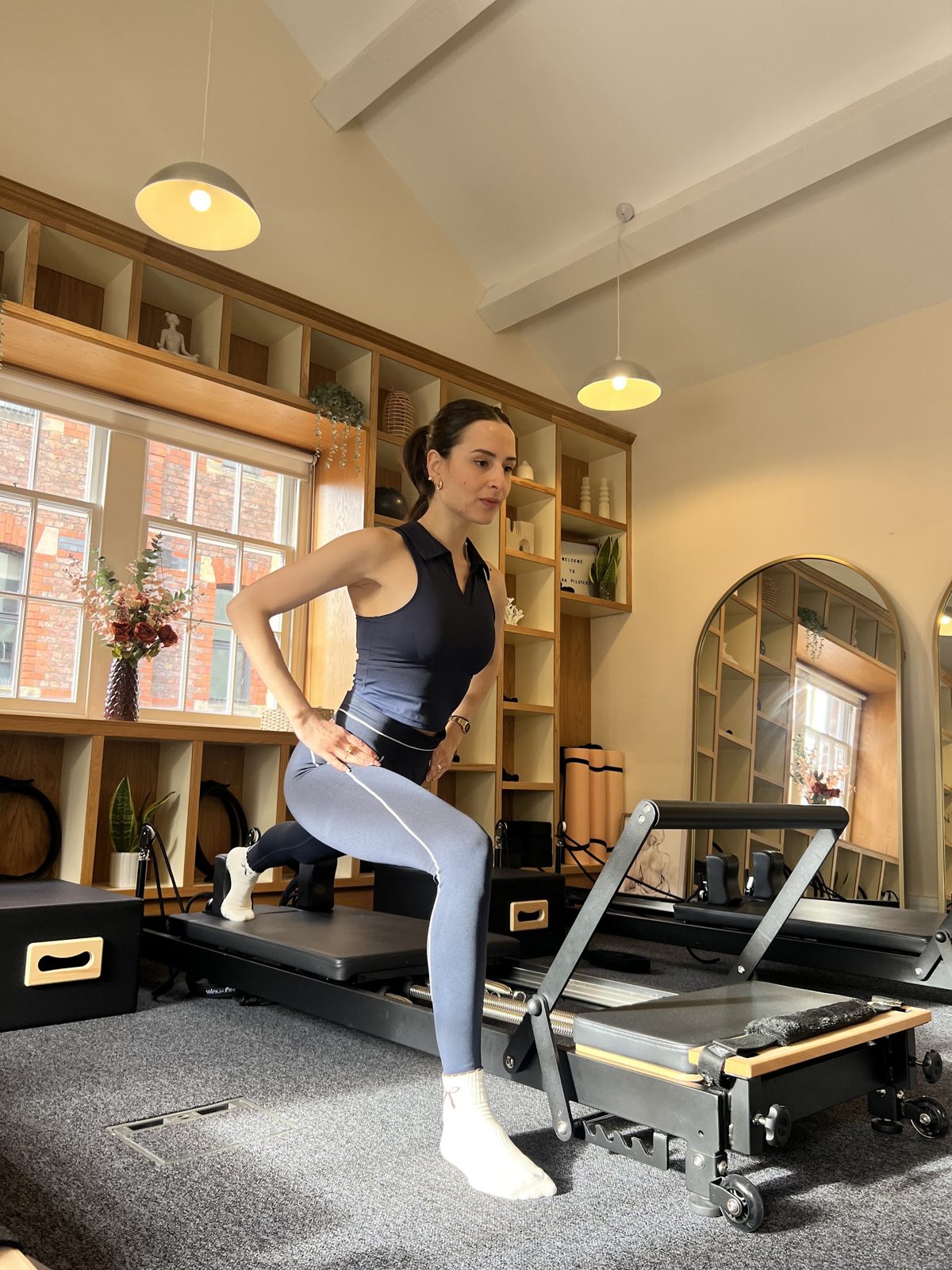 An instructor in a lunge on a Reformer in the Casa Pilates studio